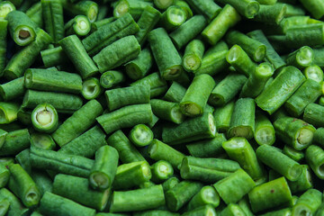 The texture of fresh green long bean pieces piled together. These vegetable pieces are ready to be cooked as a healthy ingredient, traditional food, or vegetarian dish.