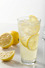 Tall glass sparkling lemonade with lemon slices and ice