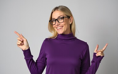 Middle age beautiful blonde woman wearing casual purple turtleneck sweater and glasses smiling and looking at the camera pointing with two hands and fingers to the side. High quality