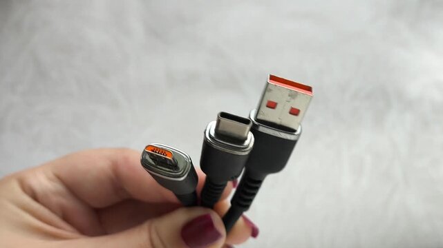 A black USB charging cable in the hand. The cable has a standard USB connector , micro and type-c