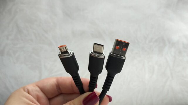A black USB charging cable in the hand. The cable has a standard USB connector , micro and type-c