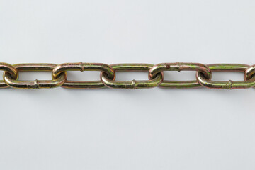 Obraz premium close-up photo of a metal chain with interlocking oval-shaped links, showing a slightly worn surface with a golden tinge