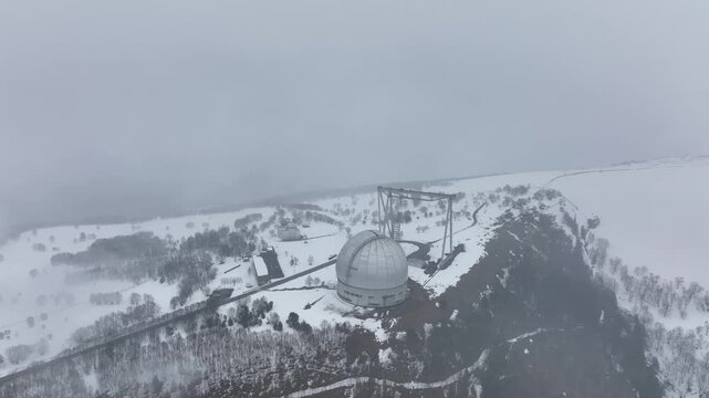 An aerial view of the BTA 6 and Special Astrophysical Observatory located in the Republic of Karachay-Cherkessia, Russia. The observatory is covered in snow on a cloudy winter day