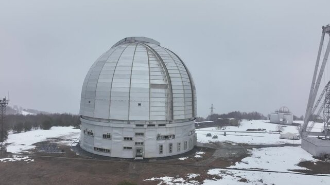 A close up of the BTA 6 and Special Astrophysical Observatory dome in the Republic of Karachay-Cherkessia, Russia. The observatory is covered in snow on a cloudy winter day