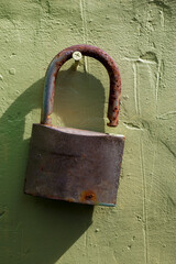 Old rusty padlock on the green painted wall of the building.
