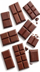 Several rectangular blocks of dark chocolate, some broken, lie scattered on a white surface, casting soft shadows