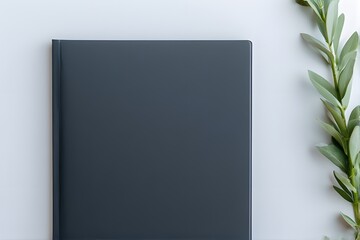 Elegant dark gray notebook or journal resting beside fresh green leaves, perfect for creative projects and mindful note-taking.