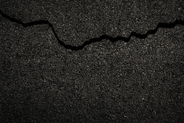 Dark cracked asphalt road surface texture with broken background.