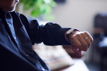 腕時計で時間を確認する日本人シニア男性の手元