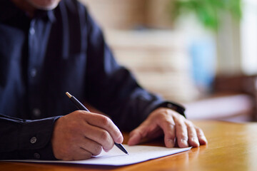 書類を書く日本人シニア男性の手元