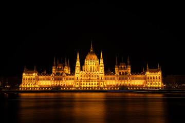 Fototapeta premium Long Exposure View of Hungarian Parliament Building and Danube River Illuminated at Night in Budapest, Hungary