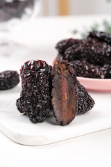 Dried Black Jujube Dates Cut Open Showing Interior on White Plate