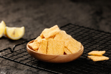 Handmade crispy crackers in wooden bowl with lemon on cooling rack - homemade snack food photography