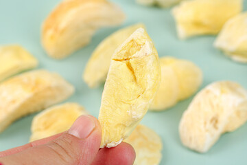 Freeze Dried Durian Fruit Slices - Hand Holding Golden Tropical Specialty Snack on Mint Background