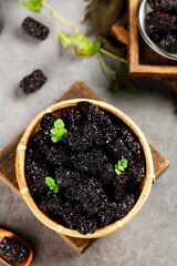 Black Dried Jujube Fruits in Bamboo Basket - Healthy Chinese Superfood Snack with Fresh Mint Leaves