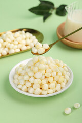 Fresh White Corn Kernels in Bowl with Spoon on Green Background - Healthy Breakfast Ingredient