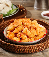 Golden Crispy Fried Chicken Nuggets on Platter with Seasoning Being Added