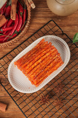 Spicy Red Chili Sticks Weilong Style Asian Snack Food on Wooden Table with Fresh Peppers and Spices