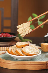 Chopsticks Picking Up Fried Tofu with Sliced Tofu Rounds on Plate - Asian Vegetarian Cooking