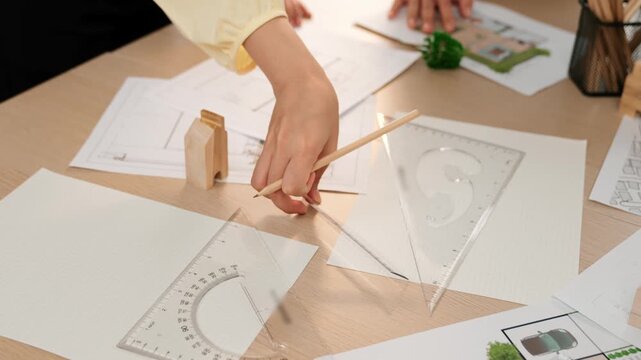 A video of architect use measurement tools and pencil to measure blueprint. Architect design house construction on a table at studio, with architectural plan scattered around. Focus hand. Delineation.