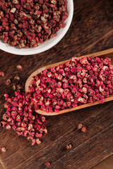 Dried Red Sichuan Hanyuan Peppercorns in Wooden Spoon and Bowl on Rustic Wood Background