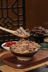 Fresh Fried Grasshoppers in Traditional Bowl - Shandong Asian Cuisine Delicacy with Wooden Spoon