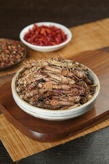 Shandong Fried Grasshoppers Traditional Chinese Insect Food Delicacy on Bamboo Serving Board