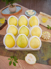 Fresh Cream Guava Fruits in Protective Mesh Display with Traditional Asian Tea Setting on Wooden Board