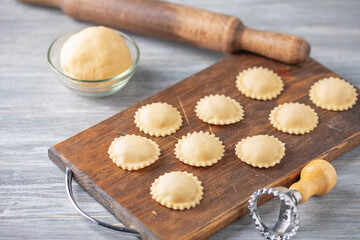 Homemade uncooked ravioli pasta  on wooden board.