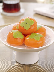 Asian Persimmon Sweets with Green Leaves on White Cake Stand - Traditional Festival Dessert