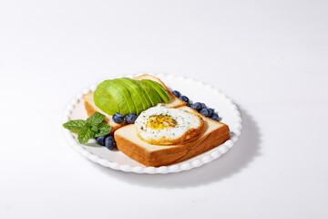 Heart-shaped egg in toast with avocado and blueberries healthy breakfast plate