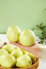 Fresh Green Guava Fruits in Wooden Bowl with Hand Display on Soft Natural Background