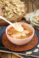 Traditional Chinese Lily Bulb Soup with Mushrooms and Red Dates in Pink Bowl on Wooden Table