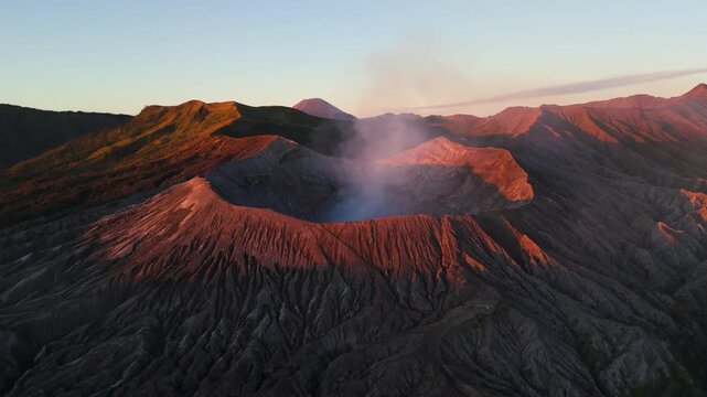 Peaceful volcano landscape with mount bromo crater during golden sunrise time. Mount semeru in distance. Aerial wide shot. Golden hour scene.
