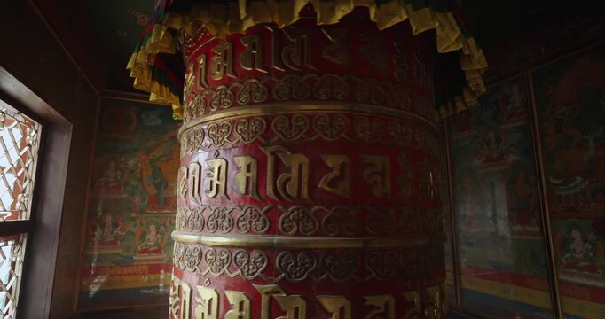 Big prayer wheel rotates inside Boudha Stupa temple, Kathmandu, Nepal. Light enters through window, symbolizing rays of hope, devotion, and peace in Buddhist heritage site of meditation and culture