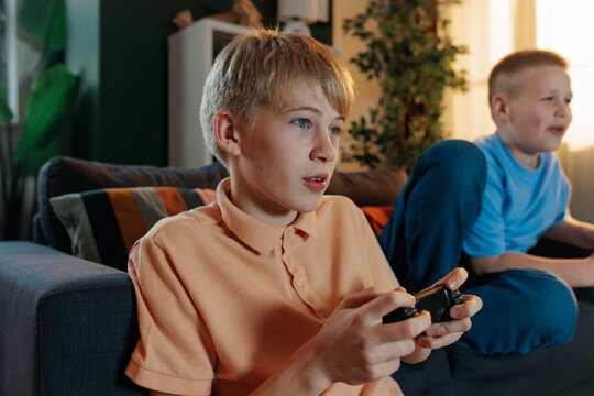 Concentrated gen z boys playing video games at home - Powered by Adobe