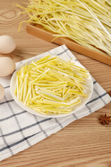 Sautéed Leeks Julienned in White Bowl with Fresh Eggs on Wooden Kitchen Counter