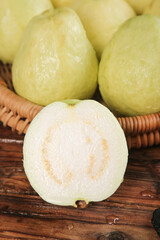 Fresh Guavas in Basket with Cut Half Showing Creamy White Flesh and Seeds on Wood