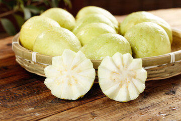Fresh Guavas with Cream Soft-Centered Flesh in Wicker Basket on Wooden Surface