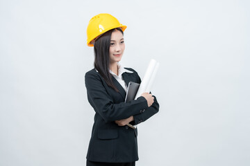 In a crisp white background studio, the Asian female engineer presents a blueprint with a laptop beside her, illustrating innovative solutions for challenges faced in the modern industry.