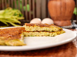 Fresh leek quiche slices with eggs showing golden pastry crust and vegetable filling on rustic kitchen table