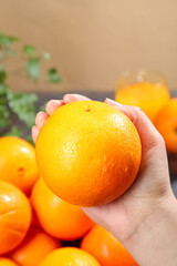 Hand Holding Fresh Navel Orange with Sweet Citrus Fruits - Healthy Vitamin C Food Concept