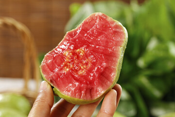 Fresh Red Guava Fruit Half with Soft Pink Flesh and Seeds Held in Hand