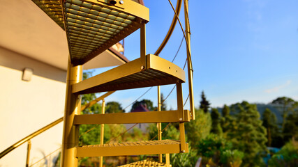 Steel spiral gold staircase on the terrace with plants and plants in pots background.
