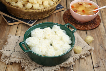 Lotus Root Slices with Traditional Asian Soup and Dried Ingredients on Wooden Table