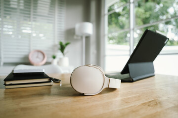 A modern home office with a laptop, headphones, notebook, and pen on a wooden desk, creating a clean and productive workspace atmosphere.