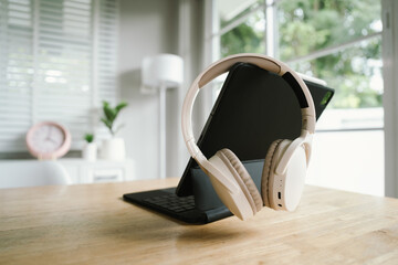 A modern home office with a laptop, headphones, notebook, and pen on a wooden desk, creating a clean and productive workspace atmosphere.