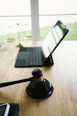 A judge's gavel placed on a wooden desk beside a laptop, symbolizing law, justice, court decisions, and legal proceedings in a modern office.