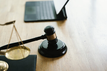 A judge's gavel placed on a wooden desk beside a laptop, symbolizing law, justice, court decisions,...