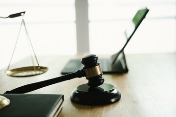 A judge's gavel placed on a wooden desk beside a laptop, symbolizing law, justice, court decisions,...